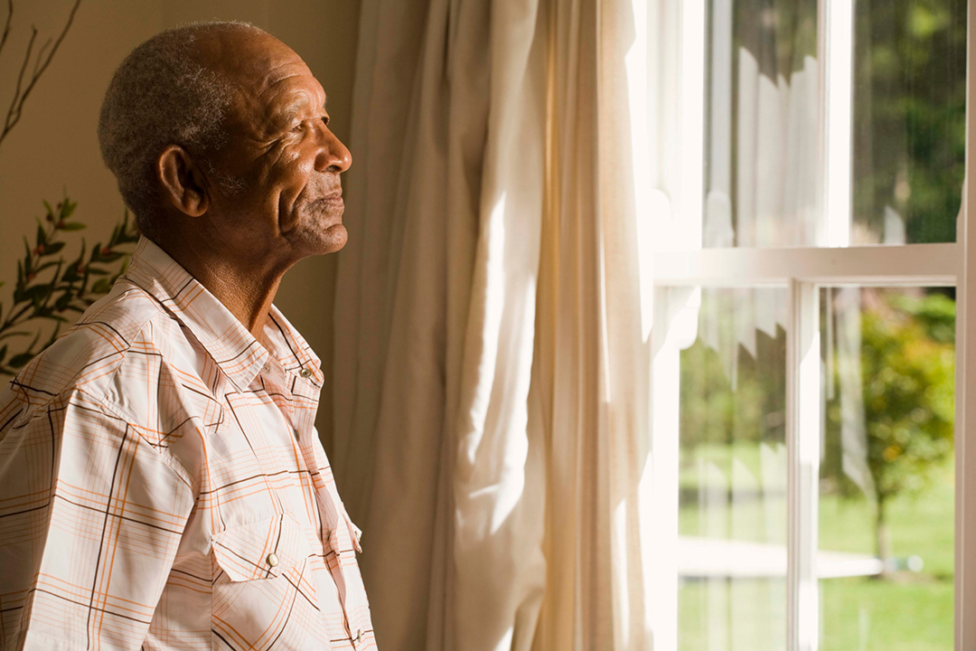 Lonely old man looking out of the window.